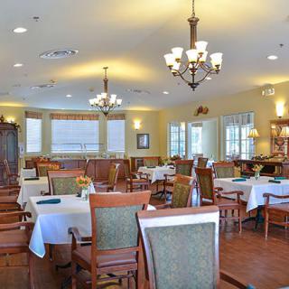 An elegant dining area with multiple tables, chandeliers, and large windows.