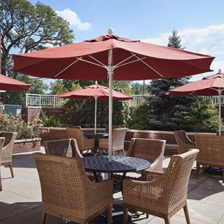 A cozy outdoor patio with wicker chairs and tables under large red umbrellas.