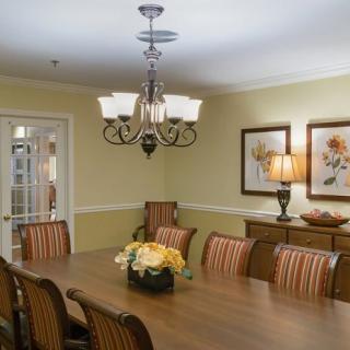 A well-decorated dining room with a large table, elegant chairs, and a chandelier overhead.