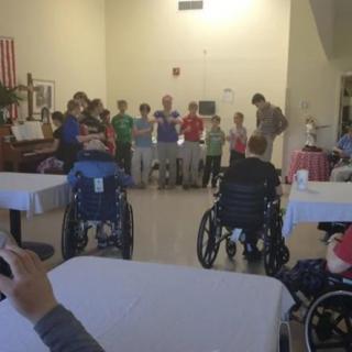 A group of elderly people in wheelchairs enjoying a community event indoors.