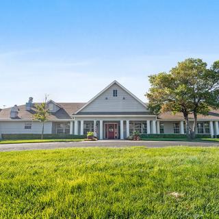 A large residential house with a neatly trimmed lawn and clear blue sky.