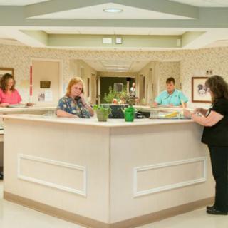 Hospital staff attending to duties at a central nurse station.