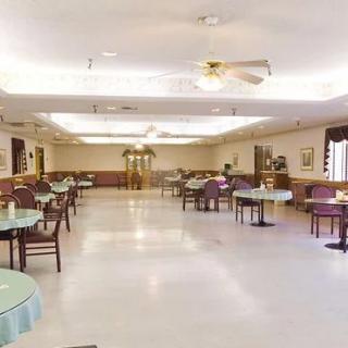 Spacious dining area with multiple tables and chairs, featuring ceiling fans and decorative elements.