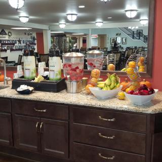 A well-stocked refreshments area in a hotel lobby featuring fresh fruits and beverages.