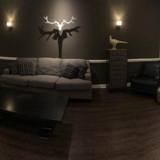 A cozy living room with modern decor featuring a gray sofa, wall-mounted sculpture, and warm lighting.