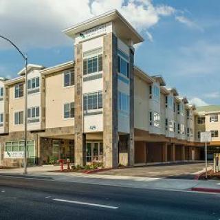 A modern apartment complex on an urban street corner during the day.