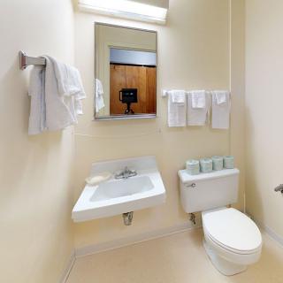A minimalist bathroom with a sink, toilet, and neatly arranged towels.