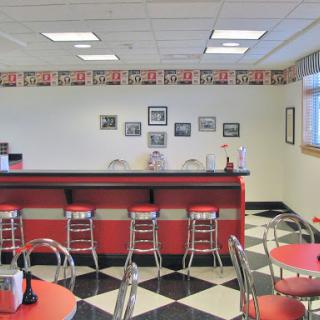 A retro-style diner with red bar stools and a black-and-white checkered floor.
