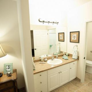 A well-lit bathroom featuring a sink with a countertop, decorative items, and framed pictures on the wall.