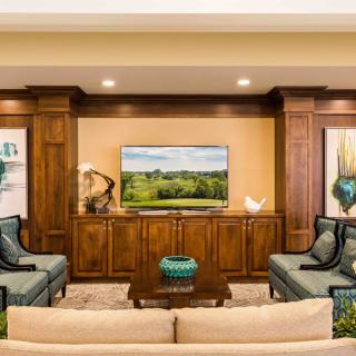 A well-decorated living room with wooden cabinetry, a television, and comfortable seating.