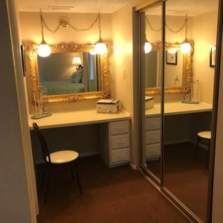 A well-lit vanity area with a mirror and desk, featuring elegant decor.