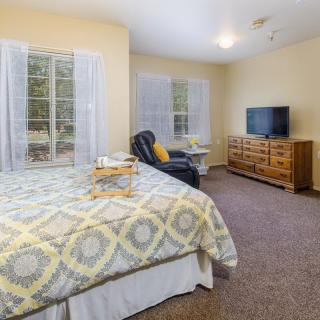 A cozy bedroom with a large bed, TV, and comfortable chair.