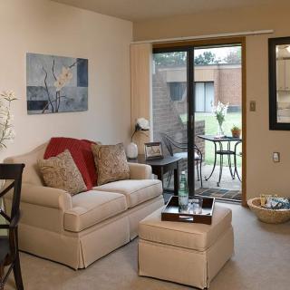 A cozy living room with a sofa, coffee table, and patio doors leading outside.