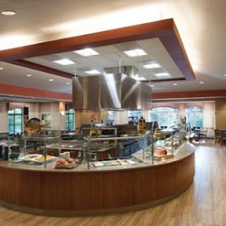 A modern cafeteria featuring a self-service food station and ample seating.