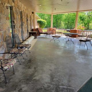 A spacious patio with stone walls features outdoor seating arrangements, surrounded by greenery.