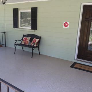 A cozy front porch with a bench and decorative cushions.