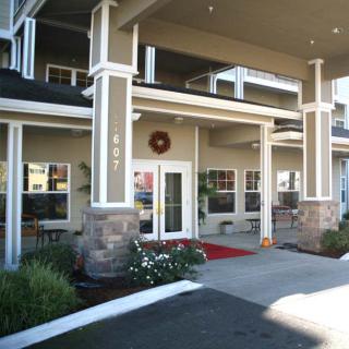 Entrance to a modern building with decorative columns and landscaping.