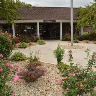 A well-maintained building entrance surrounded by colorful flowers and lush greenery.