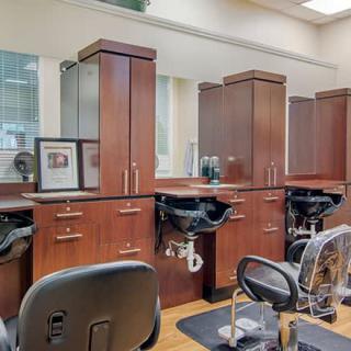 An interior view of a stylish hair salon with wooden cabinets, mirrors, and shampoo stations.