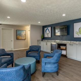 A modern living room with blue chairs and a coffee table, featuring contemporary artwork on the walls.