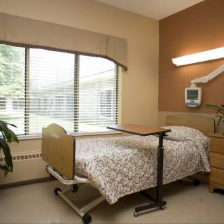 A clean and well-organized hospital room with a single bed near a large window.