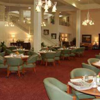 An elegant restaurant interior with neatly arranged tables and chairs under warm lighting.