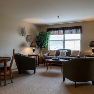 A cozy living room with a sofa, chairs, and a window allowing natural light.