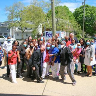 A diverse group of individuals gathered outdoors for a celebratory event, all wearing masks.
