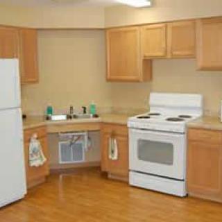 A simple kitchen with wooden cabinets, a white stove, and refrigerator.