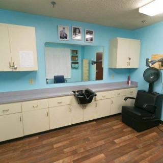 A well-organized hair salon interior with a styling chair, cabinets, and a mirror against blue walls.