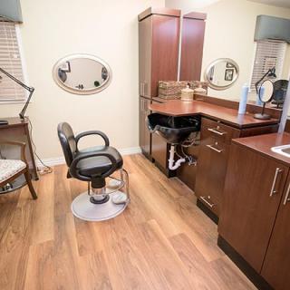 A modern hair salon interior with a styling chair, mirror, and sink.