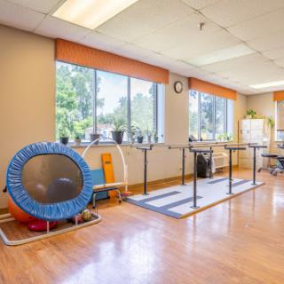 A bright and spacious therapy room equipped with exercise equipment, including a trampoline, ideal for rehabilitation activities.