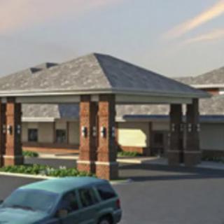 A building with an entrance and a parking lot in front, featuring a parked car.