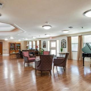 A spacious lounge area with comfortable seating and a piano, featuring wooden floors and warm lighting.