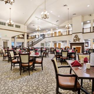 A spacious and elegantly designed dining room with neatly arranged tables and decorative lighting.