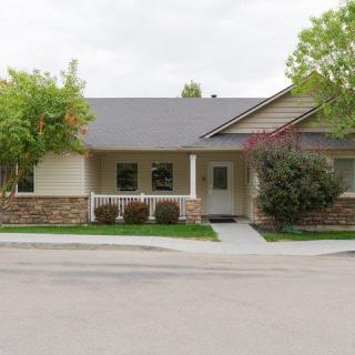 A suburban house with a porch and a small front yard surrounded by trees.