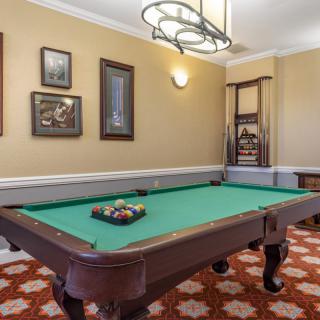 A classic billiard room featuring a pool table with decorative wall art.