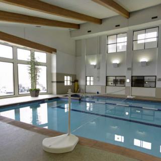 An indoor swimming pool with large windows allowing natural light.