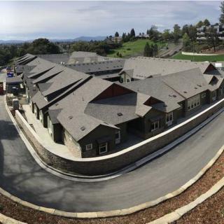 Aerial view of a residential building with multiple rooftops and surrounding roads.