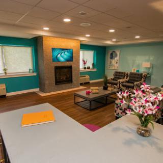 A modern and inviting waiting room featuring comfortable seating, a cozy fireplace, and vibrant blue walls.