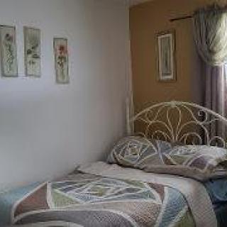 A cozy bedroom with decorative artwork and a patterned quilt on the bed.