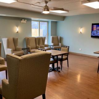 A cozy living room with comfortable chairs, tables, and a television.