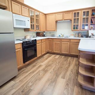 A modern kitchen with wooden cabinets, stainless steel appliances, a microwave, oven, and refrigerator.