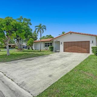 A suburban single-story house with a driveway and garage, surrounded by a well-maintained lawn and trees.