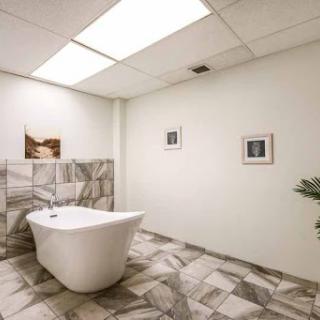 A modern bathroom featuring a stylish bathtub, decorative tiles, and framed artwork.