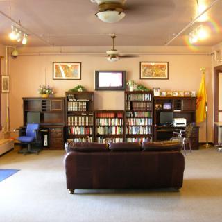 A cozy library reading area with bookshelves, a couch, and a television.