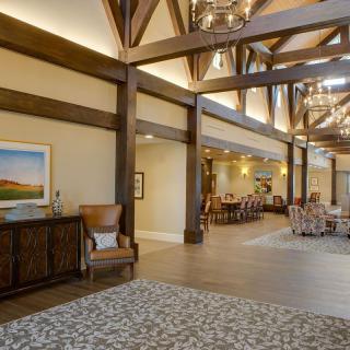 A spacious lobby area featuring modern decor with wooden beams, elegant chandeliers, and comfortable seating.