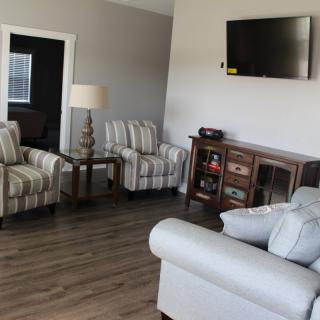 A cozy living room with modern furniture and a wall-mounted TV.