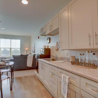 A modern open-concept kitchen and living area with light-colored cabinetry and decor.