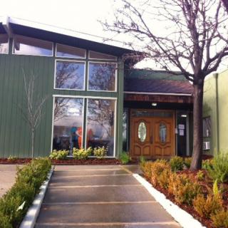 A modern building entrance with landscaped pathways and large glass windows.